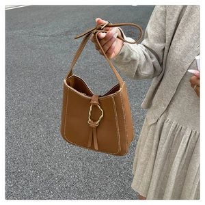 Detail of brown PU leather bag featuring white contrast stitching and gold metal buckle