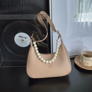 Borsa hobo beige elegante con tracolla di perle e cinturino in pelle in un interno