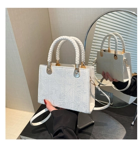 Close-up of white floral lace texture and braided round handles on the leather handbag
