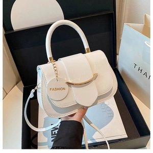 Detail der weißen Satteltasche aus Lackleder mit Goldverzierung und abnehmbarem Gurt in Box
