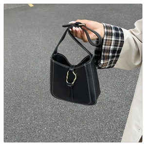 Detail of black PU shoulder bag with white contrast stitching and gold metal buckle