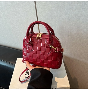 Detail shot of glossy red patent leather texture with quilted shell bag stitching