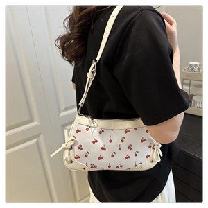 Détail du sac à l'épaule avec imprimé cerise et nœud décoratif sur le côté
