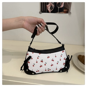 Détail du sac à bandoulière imprimé cerise avec bordure en cuir noir et clous argentés
