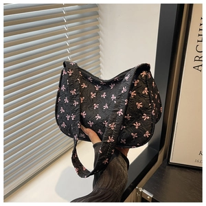 Detail of black textured handbag featuring pink bow prints and a smooth top zipper closure