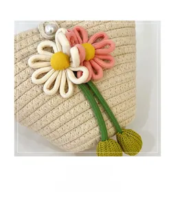 Detail der Strohtasche mit handgehäkelten Blumen und einem eleganten Perlenknopf