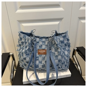 Détail du sac cabas en denim à carreaux avec bords effilochés et écusson en cuir brun