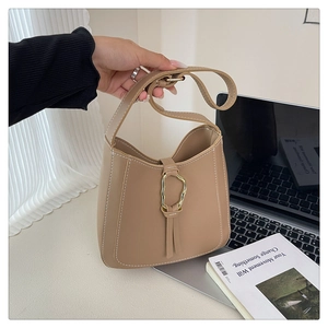 Detail of khaki PU shoulder bag with white contrast stitching and gold metal buckle