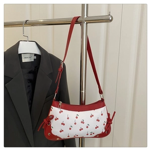 Détail du sac à main à motif cerises avec nœuds en cuir et rivets métalliques dorés