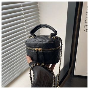 Detail of black quilted mini bag featuring gold chain strap and dual zipper closure