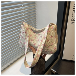 Detail of white nylon shoulder bag featuring pink bow patterns and pleated fabric texture
