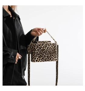 Close-up of leopard print handbag with golden V buckle and adjustable strap