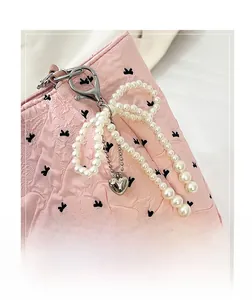 Détail du sac fourre-tout rose matelassé avec nœuds noirs et breloque en perles