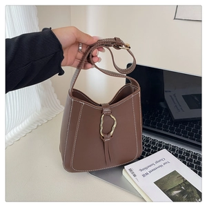 Detail of dark brown leather bucket bag featuring white contrast stitching and gold ring buckle