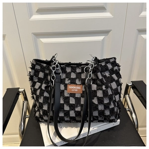 Détail du sac cabas en denim à carreaux avec bords effilochés et chaîne argentée