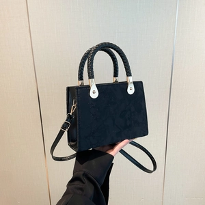 Fashionable black crossbody handbag with embossed floral texture and woven handles