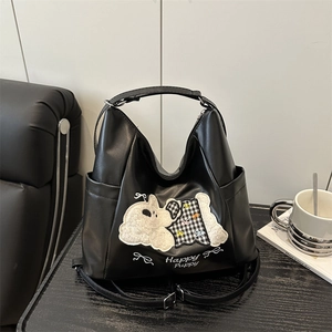 Black hobo bag with cute puppy embroidery and Happy Puppy text on a stylish desk