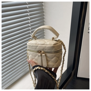 Detail of a quilted mini chain bag in cream white with gold metal hardware and leather strap