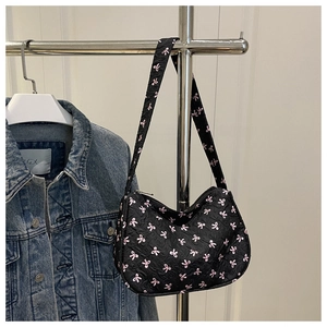 Detail of black jacquard shoulder bag with pink bow patterns on silver metal hanger