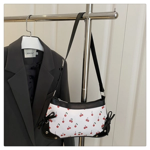 Détail du sac cerise avec nœuds en cuir noir et accents de rivets métalliques