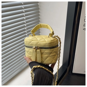Close-up of yellow quilted PU leather mini bag with gold chain strap and dual zippers