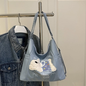 Light blue tote bag with a white puppy embroidery and Happy Puppy text on a metal hanger