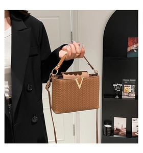 Détail du sac bandoulière tressé marron avec logo V doré et cuir synthétique texturé