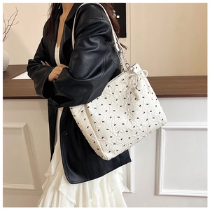 Détail du sac cabas matelassé avec imprimés nœuds noirs et breloque en perles