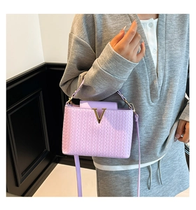 Détail du sac à main tissé lavande avec boucle en V dorée et texture élégante