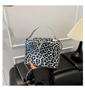 Detailed view of leopard print handbag with V-shaped metal buckle and slim shoulder strap