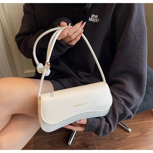 Close-up of minimalist white underarm bag featuring elegant gold Fashion & Bags lettering
