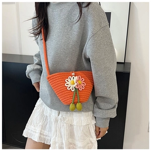 Detail der handgewebten orangefarbenen Stricktasche mit Blumen und grünem Bommel