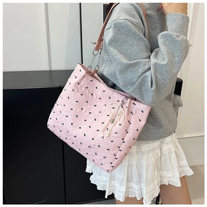 Pink bow-pattern tote bag detail with pearl pendant and leather chain shoulder strap