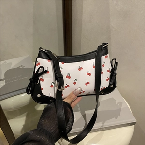 Sac baguette blanc avec imprimé cerise et nœuds noirs en situation de style de vie