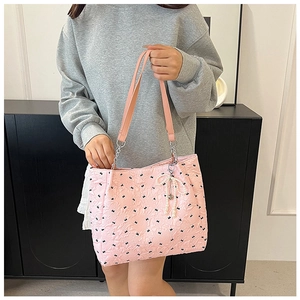 Détail du sac cabas rose en seersucker avec motifs couronnes et pendentifs perles et cœur