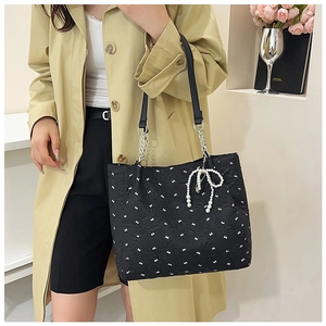 Détail d'un sac cabas en seersucker noir avec broderie nœud blanc et breloque en perle