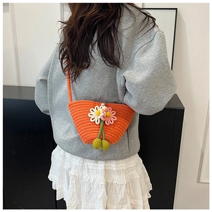 Detail of hand-woven orange mini bag with 3D floral accents and pearl button closure