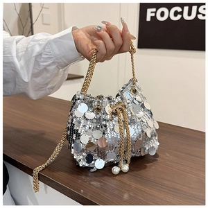 Gros plan du sac seau en paillettes argentées avec chaîne dorée et détail de perle