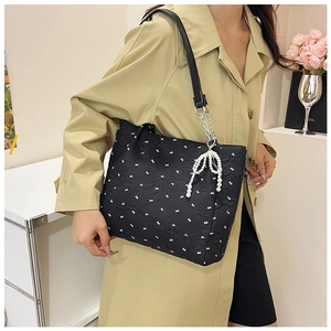 Détail du cabas plissé noir à motifs lapins avec pendentif nœud en perles élégant