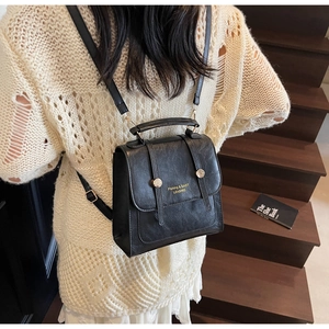 Détail d'un sac à dos vintage en cuir noir avec boucles dorées et texte élégant gaufré