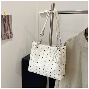 Détail du cabas blanc avec broderies nœuds, texture froissée et breloque perle