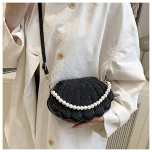 Detail of black shell-shaped bag with snakeskin texture and elegant pearl handle