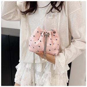 Close-up of pink drawstring bucket bag with bow embroidery and pearl accents