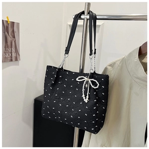 Détail du cabas noir en seersucker avec nœuds blancs et pendentif en perles