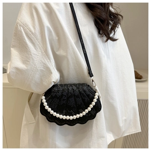 Detail of black shell-shaped handbag with snake pattern texture and pearl chain