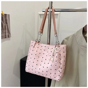Détail du sac cabas gaufré rose avec nœuds noirs et breloque papillon en perles