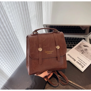 Detail of dark brown faux leather backpack with gold buckles and chic flap design