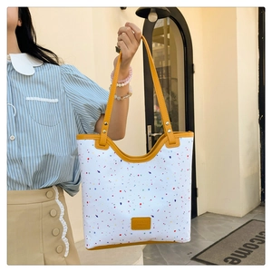 Detailed outdoor shot of a white tote bag with colorful polka dots and yellow leather straps