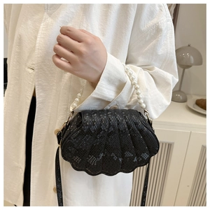 Detail of black shell-shaped bag with snake-skin texture and elegant pearl handle
