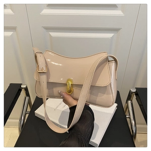 Detail of glossy beige patent leather bag featuring a gold cylindrical twist lock